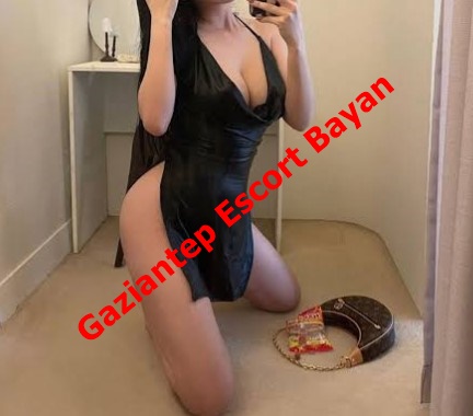 Selfie of a woman kneeling on a carpet in a black outfit, taking a mirror photo with a red escort watermark across the image.
