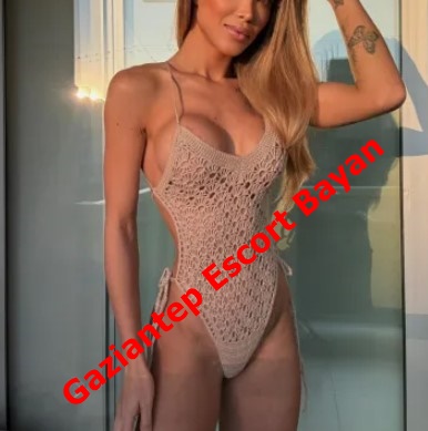 Woman in a beige crochet one-piece swimsuit posing in front of a glass door, with red diagonal text 'Gaziantep Escort Bayan' across her torso.