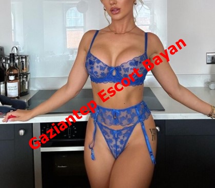 Woman in blue lace lingerie posing in a modern kitchen with a bold red diagonal 'Gaziantep Escort Bayan' watermark, indicating an escort advertisement.