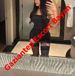 Woman in a short black dress and thigh-high stockings taking a mirror selfie in a bathroom; red watermark reads Gaziantep Escort Bayan.